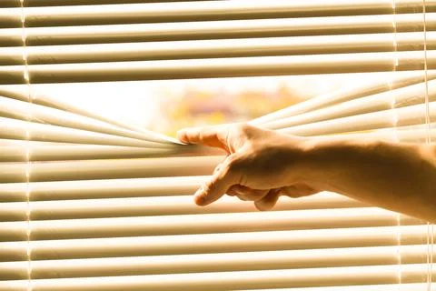 Man separating slats of white blinds indoors, closeup Fotos de archivo
