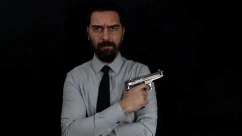 Man with serious face keeps his arms crossed to the body with a gun in his hand Stock Footage 143486663