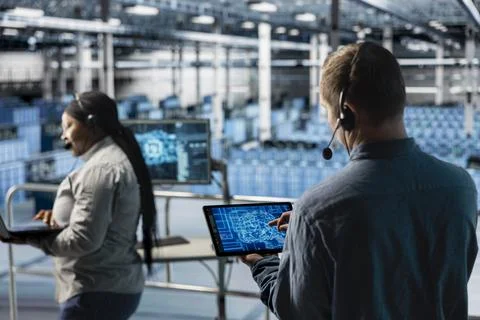 Man in server farm using AI tech on device, talking in headset mic 写真素材