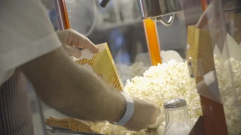 Man serving up fresh popcorn into bag Stock Footage 98765871