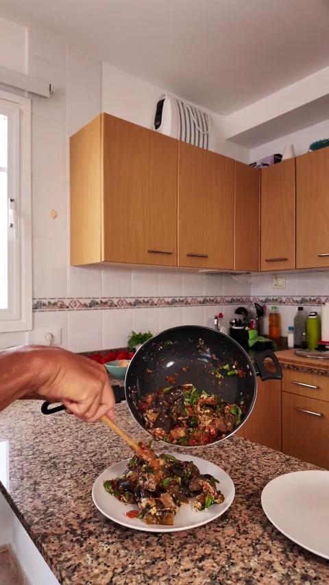 Man serving a healthy vegan dish of eggplants from a wok Stock Footage 344690588