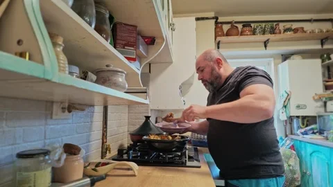 Man Serving Himself a Plate of Homemade Tajine Food in Her Kitchen Stock Footage 341669542