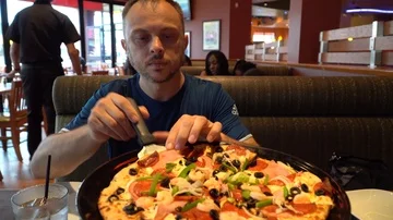 Man serving himself slice of shrimp ham pepperoni vegetable pizza in restaurant Stock Footage 85574285