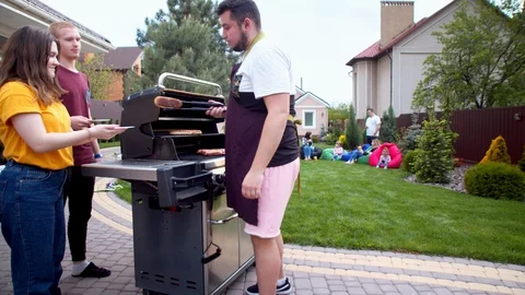 Man serving hot dogs to young friends Stock Footage 130066317