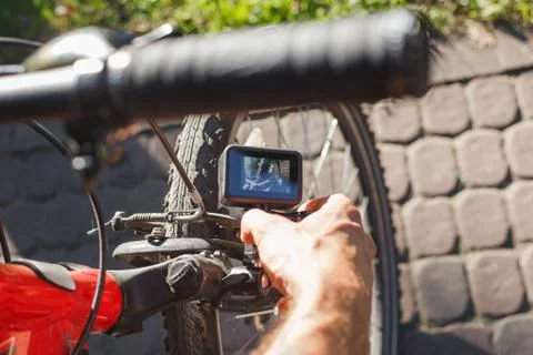 A man sets up an action camera that is fixed next to a bicycle wheel Stock Photos
