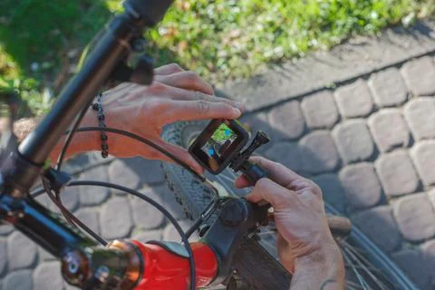 A man sets up an action camera that is fixed next to a bicycle wheel Stock Photos