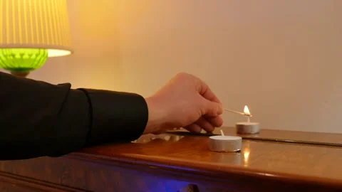 Man sets candle on fire with match. male hand with burning match lights a candle Stock Footage 145712551