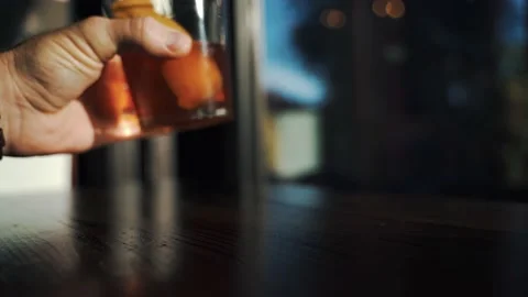 Man sets down old fashioned at window bar Stock Footage 223218417