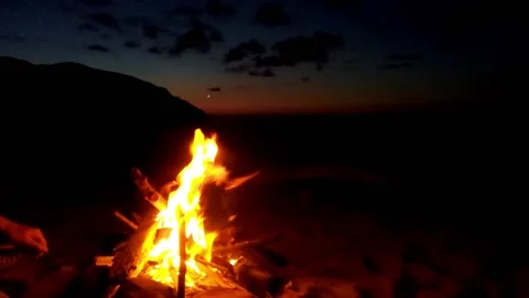 A man sets fire to the beach using wood 스톡 동영상 143976777