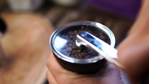 Man sets the handle on a manual coffee grinder and grinds coffee beans Stock Footage 277220675