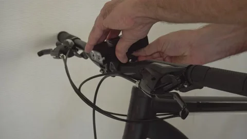A man sets a headlamp, a flashlight on the handlebars of the bike Stock Footage 159496677