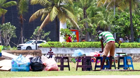Man sets up his mobile toy shop in a park between huge buildings in a busy city. 動画素材 250201265