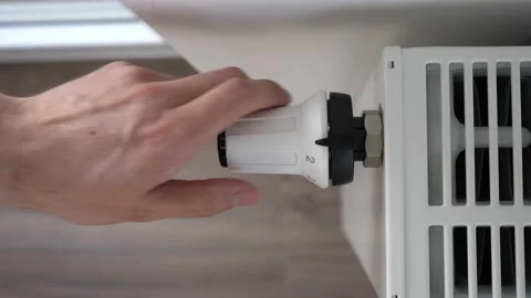 The man sets the radiator thermostat to the maximum mode Stock Footage 189966456