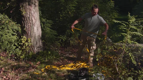 Man sets slackline between trees above the river. 스톡 동영상 140762862