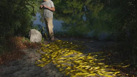 Man sets slackline between trees above the river. 스톡 동영상 140762872