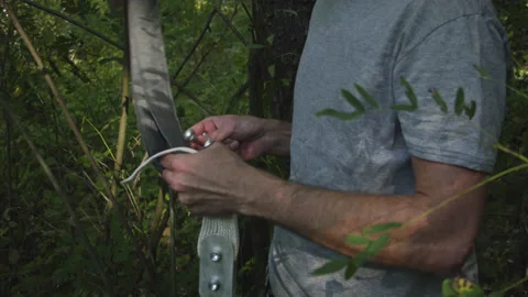 Man sets slackline between trees above the river. 스톡 동영상 140766593