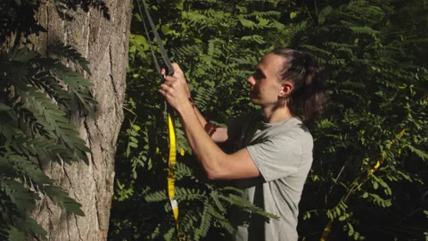 Man sets slackline between trees above the river. 스톡 동영상 140792469