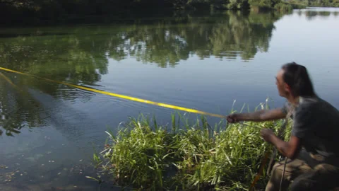 Man sets slackline between trees above the river. 스톡 동영상 140799332