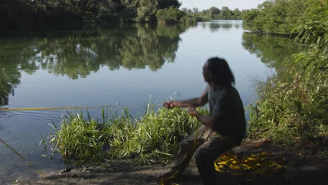 Man sets slackline between trees above the river. 스톡 동영상 140799503