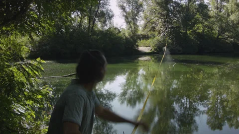 Man sets slackline between trees above the river. 스톡 동영상 140802803