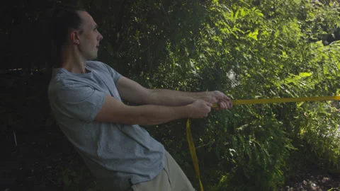 Man sets slackline between trees above the river. 스톡 동영상 140803166
