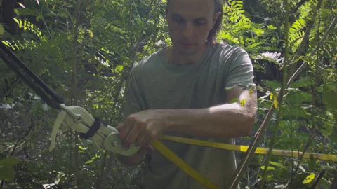 Man sets slackline between trees above the river. 스톡 동영상 140803196