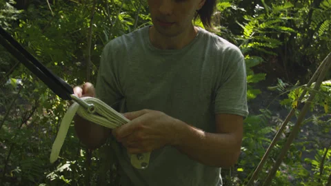 Man sets slackline between trees above the river. 스톡 동영상 140807333