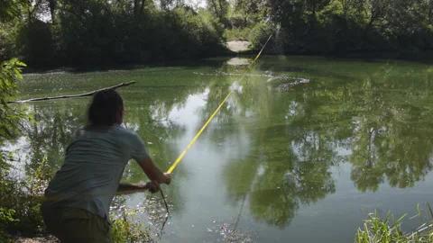Man sets slackline between trees above the river. 스톡 동영상 140807615