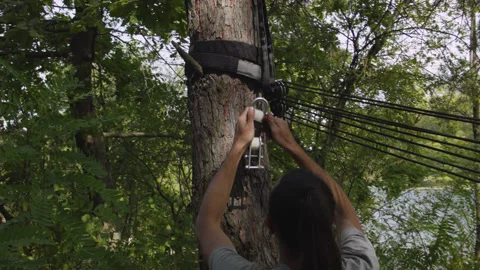 Man sets slackline between trees above the river. 스톡 동영상 140813453