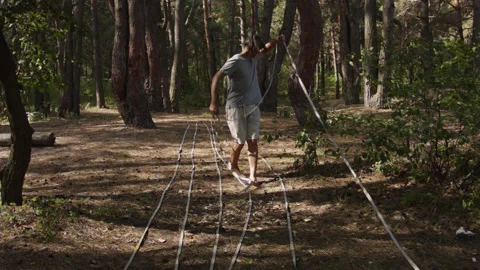 Man sets slackline between trees above the river. 스톡 동영상 140813528