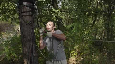 Man sets slackline between trees above the river. 스톡 동영상 140816235