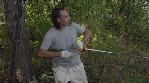 Man sets slackline between trees above the river. 스톡 동영상 140816383