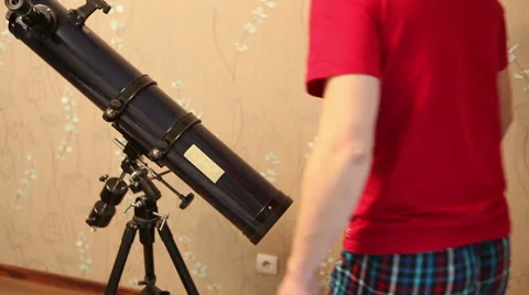 Man sets up a telescope in the room Stock Footage 60423599