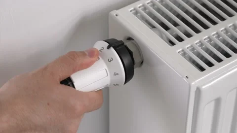 The man sets the thermostat of the heating radiator to medium economy mode Stock Footage 189964877