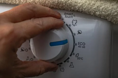 A man sets the washing program on the thermostat of an automatic washing ma.. Stock Photos