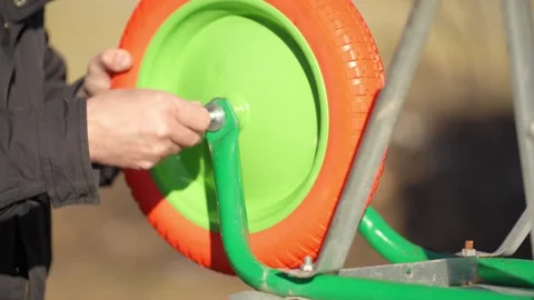 A man sets a wheel on a cart. A man screws a bolt on a cart. 스톡 동영상 305410873
