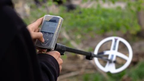 A man sets up a wireless metal detector to search for treasures underground. Stock Photos