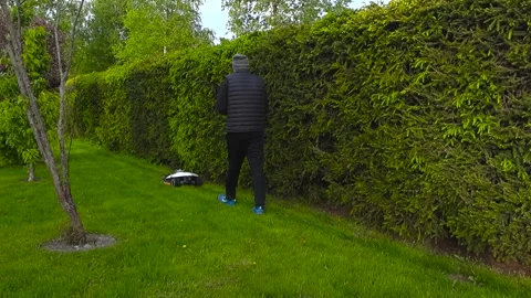 Man Setting Up Boundary for Robotic Lawn Mower in Backyard Garden Stock Footage 336651965