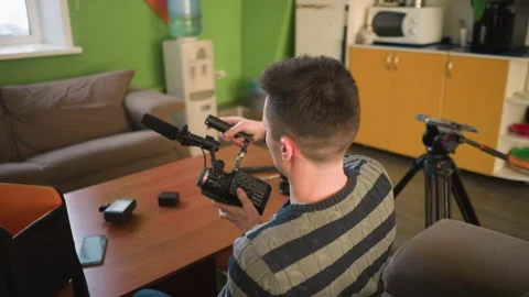 Man setting up camera with microphone in home studio, adjusting equipment Stock Footage 317587403