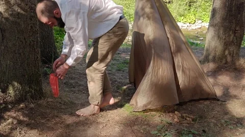 Man setting up camping tarp shelter between trees in mountain forest Vídeo Stock 344894354