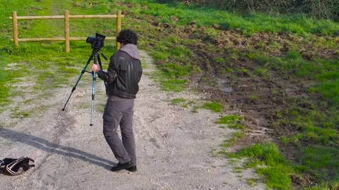 Man Setting Up His Camera On Tripod Outdoors - Drone Shot Video stock 269911195