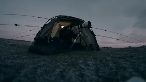 A man setting up a huge camera and lens in a tent Stock Footage 327325504