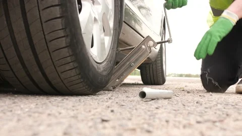 The man is setting the jacket under the car to change the flat tire Stock Footage 131119715