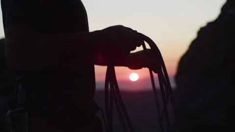 A man setting up a rope for rock climbing at sunset Stock Footage 264139595