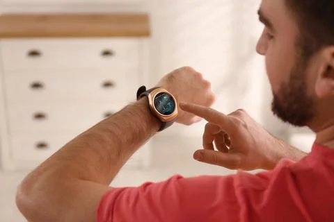 Man setting smart home control system via smartwatch indoors. App interface.. Stock Photos