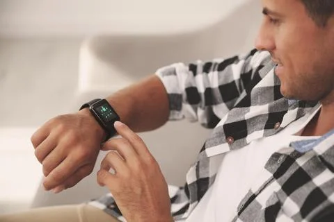 Man setting smart home control system via smartwatch indoors. App interface.. Stock Photos