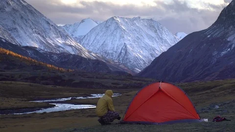 The man is setting up the tent on the background of mountain landscape. 4k Video stock 81500356
