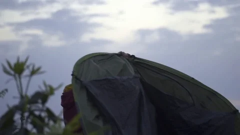 Man setting up a tent on a camping trip at dusk Stock Footage 72524206