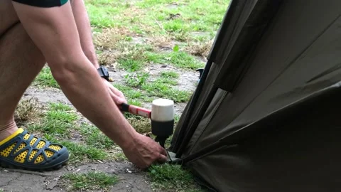 Man setting up tent on camping trip close up. Fishing tent on shore of river Stock Footage 220948204