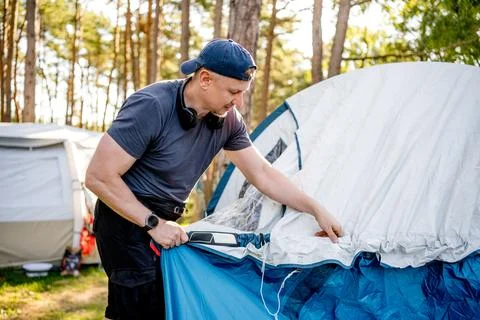 Man setting up a tent in a pine forest Stock Photos